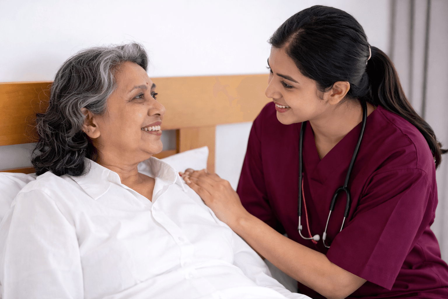 Caregiver and senior sharing tea and smiling on a sofa